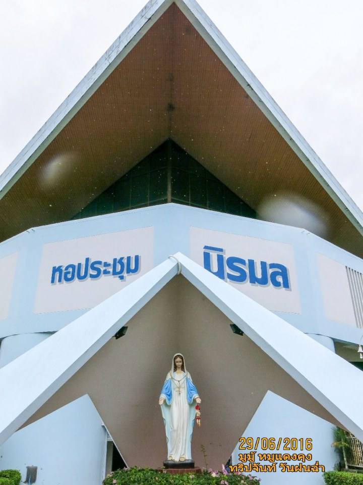เดินตรงผ่าน สถานรับเลี้ยงเด็ก มาทางด้านหลังอาสนวิหาร ตรงลานจอดรถ จะพบ หอประชุมแม่พระนิรมล